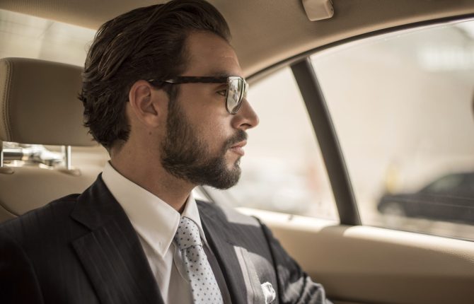 Young businessman looking out from car backseat, Dubai, United Arab Emirates